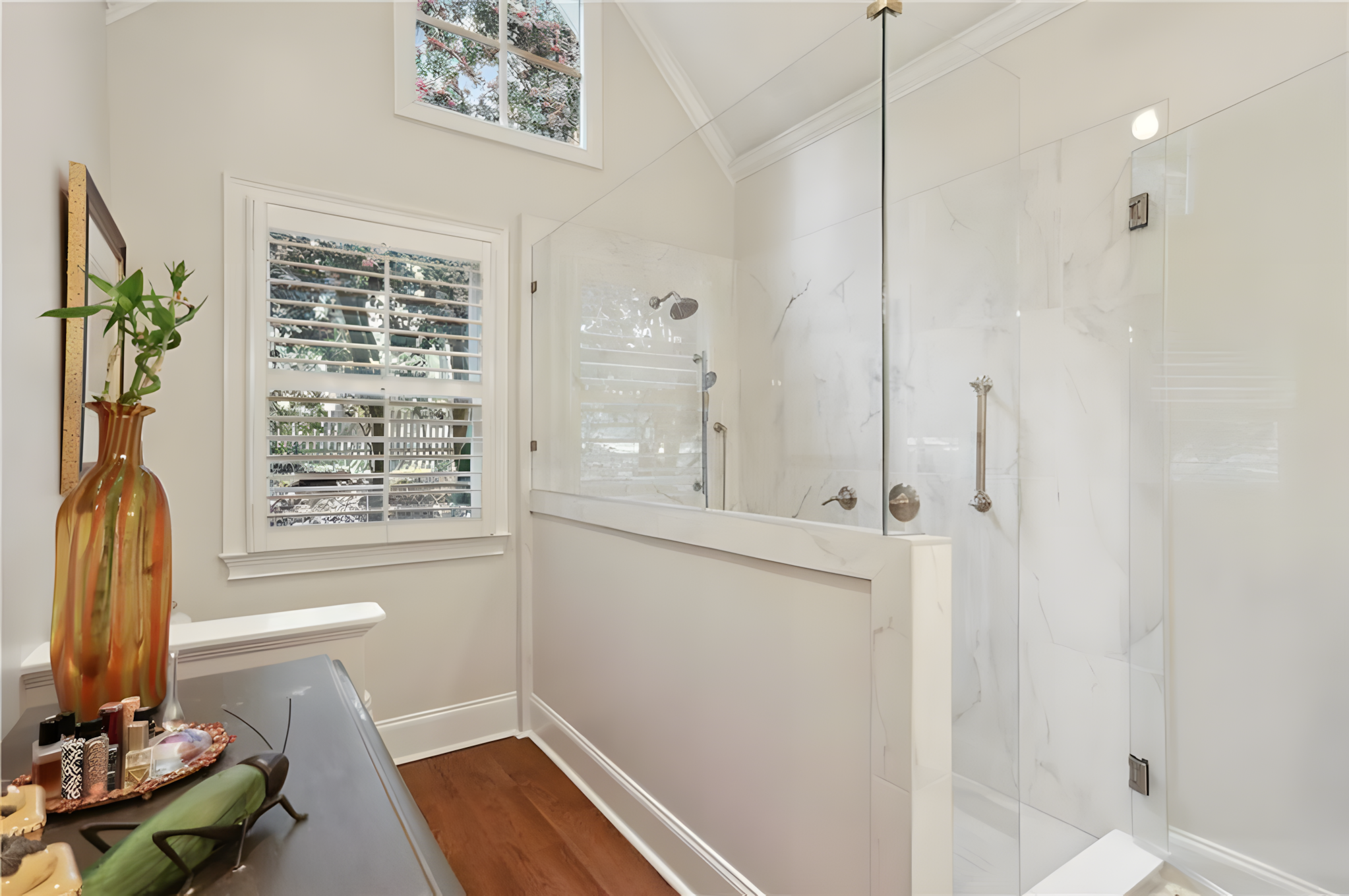 master bathroom shower with white marble tile and white half wall