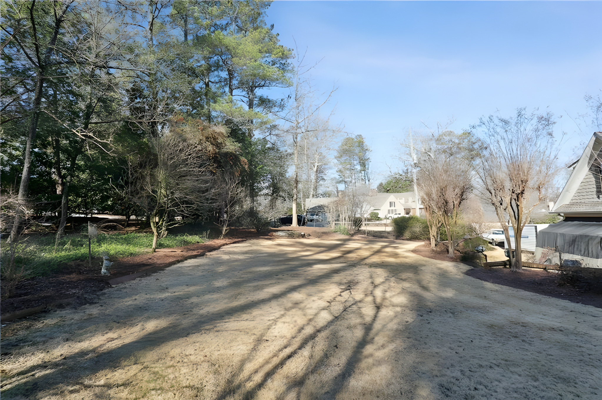backyard land with rear exterior of grey home in distance