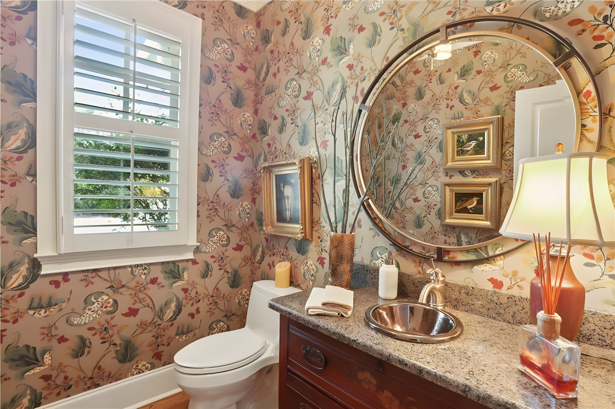 small bathroom with beige red floral wallpaper and circular mirror