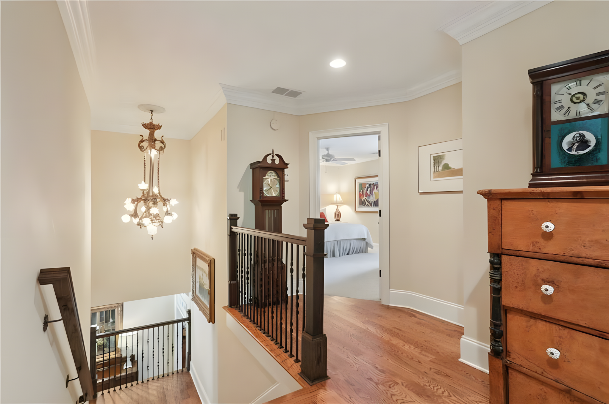 upstairs hallway with grandfather clock and hanging light fixture over staircase