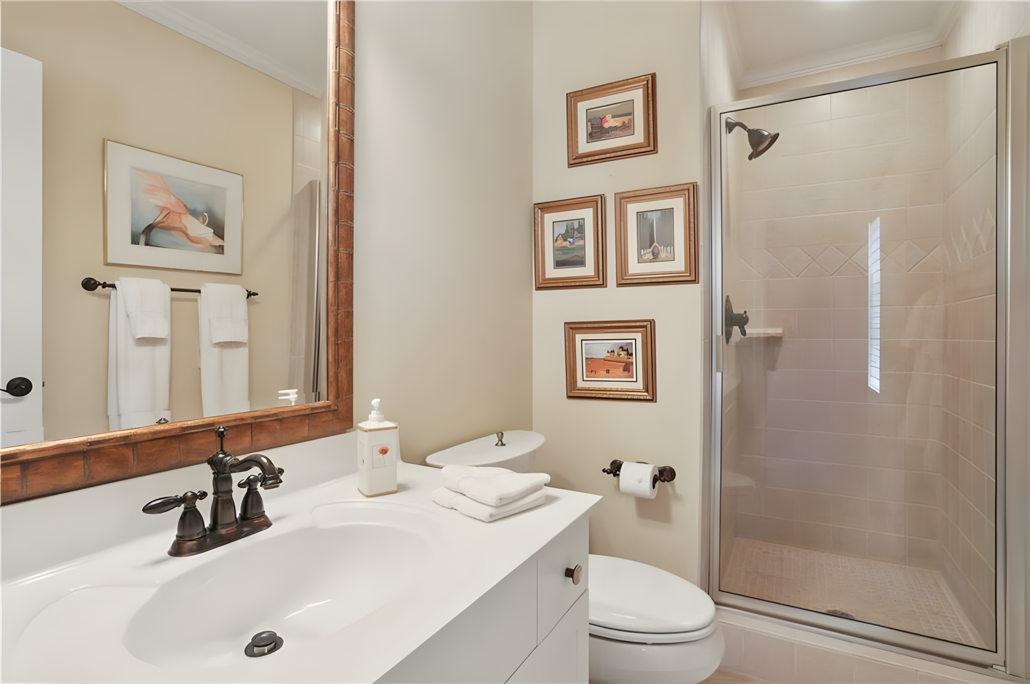 small bathroom showing small frame paintings on wall by toilet and shower tub door