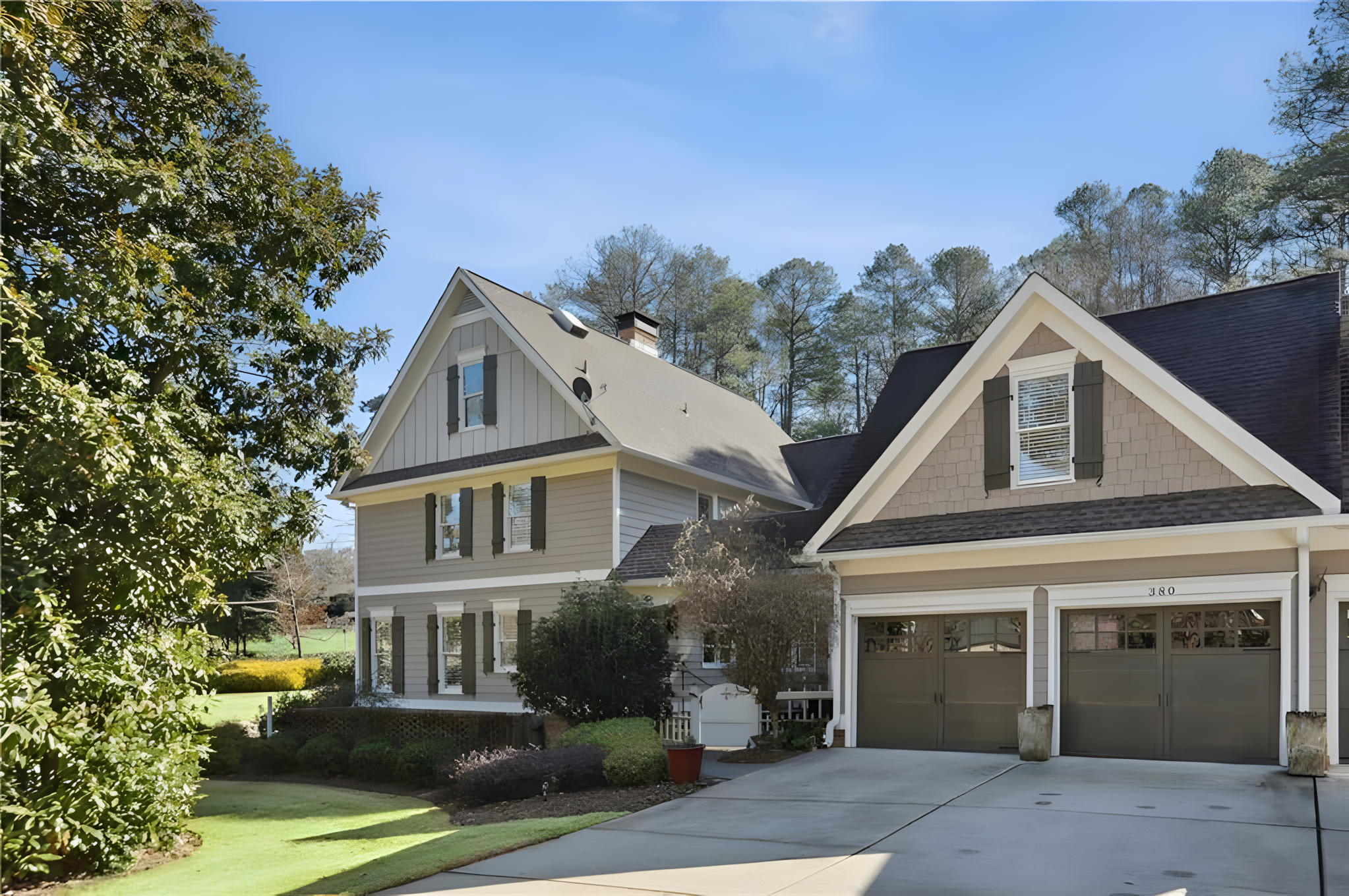 front of grey exterior home with two garage doors