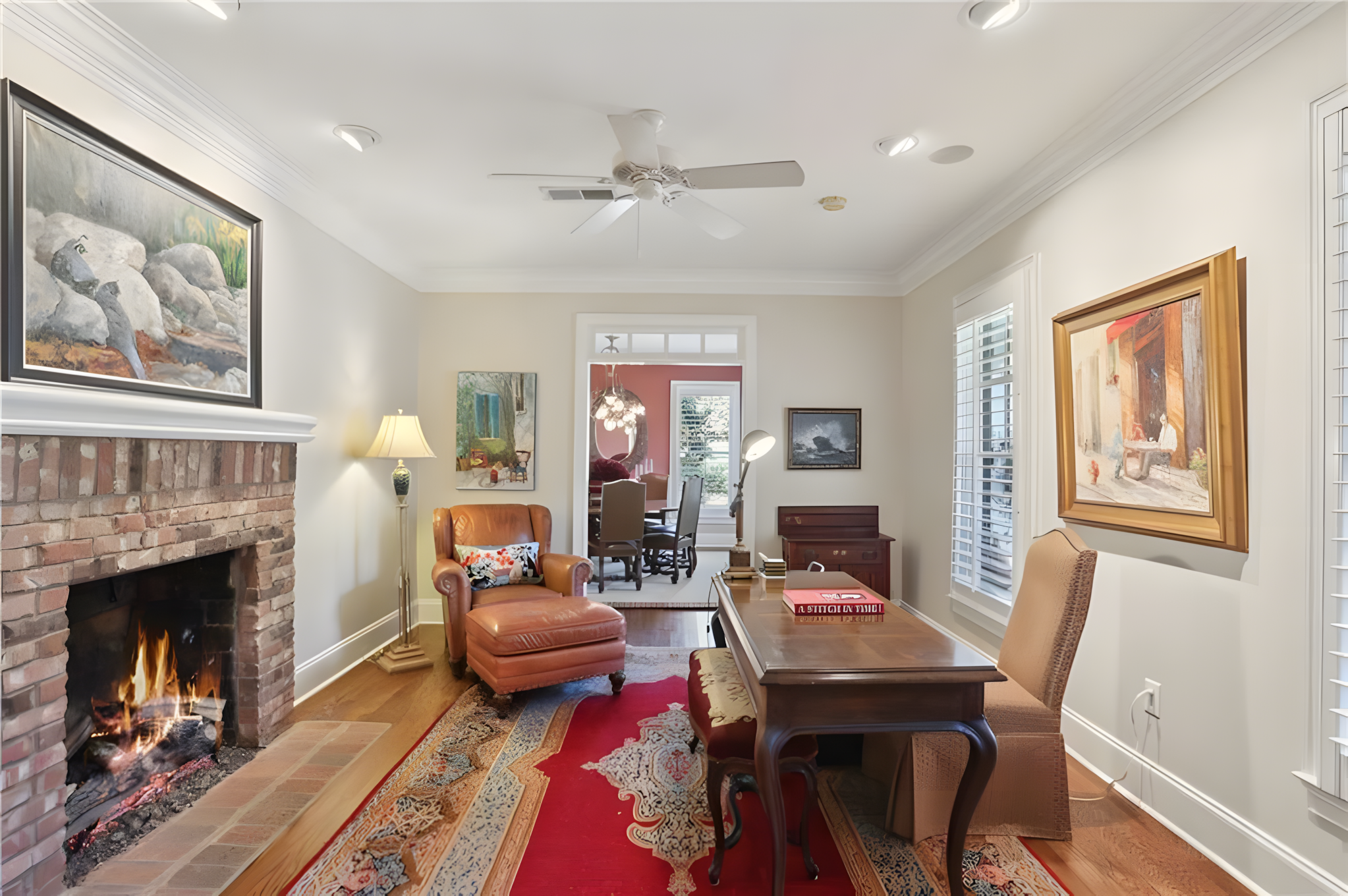 office with fireplace, red rug, antique table, chairs, and brown sofa